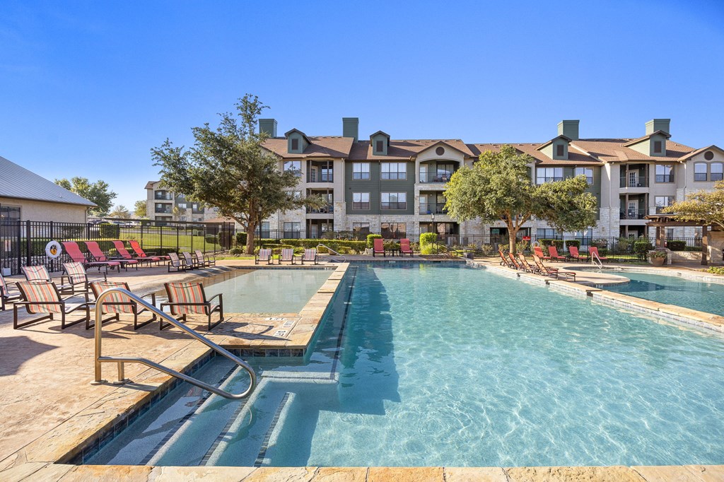 pool with chairs and apartment buildings at The Fairways at Star Ranch, Hutto, Texas