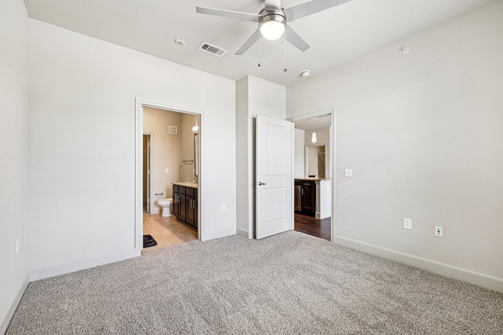 A room with a ceiling fan and carpeted floor.