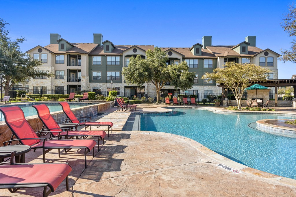 commons pool with chairs and an apartment building at The Fairways at Star Ranch, Hutto