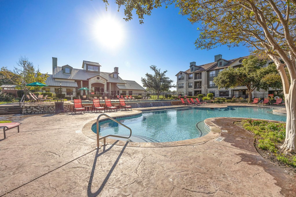 a resort style pool with chairs and a building in the background at The Fairways at Star Ranch, Hutto, TX, 78634