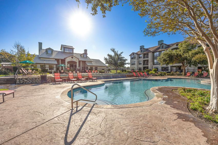 a resort style pool with chairs and a building in the background