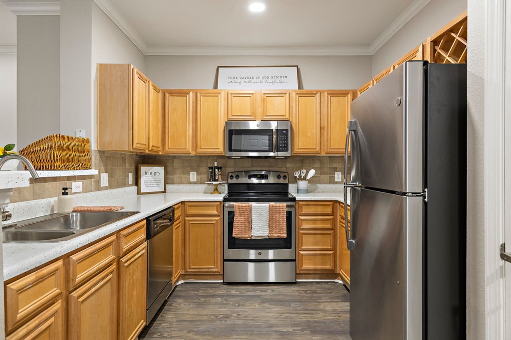 a kitchen with wooden cabinets and stainless steel appliances at The Verandah, Austin, TX
