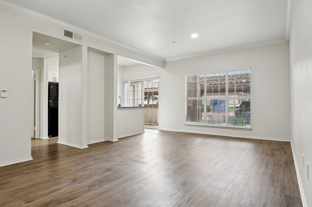A spacious room with wooden floors and white walls.