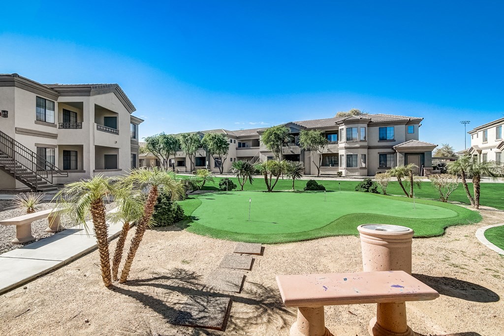 a putting green in the middle of an apartment complex with buildings  at Adiamo Palm Valley, Goodyear, AZ