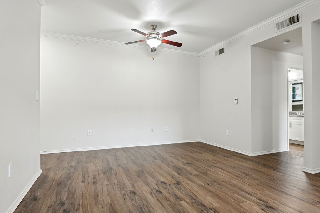 A room with a ceiling fan and wooden flooring.