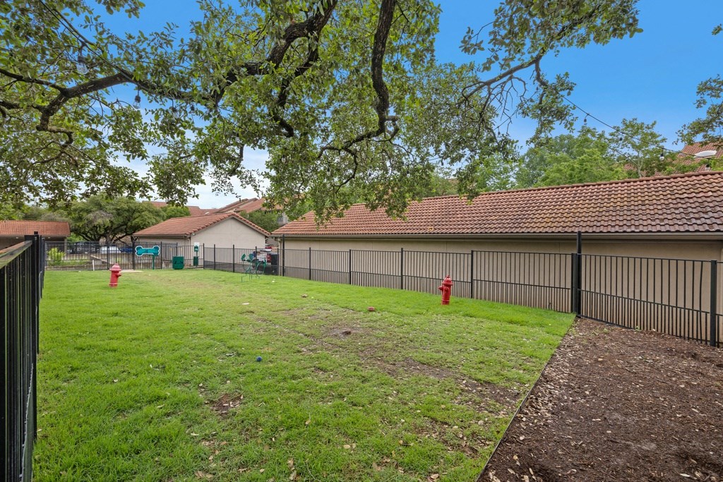 a large grassy area with a fence and a house in the background at Waters Edge Apartment Homes, Georgetown, 78626