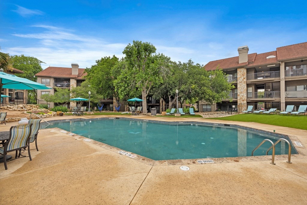 a resort style pool with lounge chairs and umbrellas at homewood suites by h at Waters Edge Apartment Homes, Georgetown, 78626