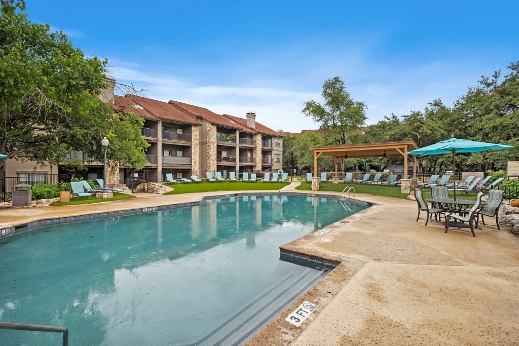 a resort style pool with lounge chairs and umbrellas at Waters Edge Apartment Homes, Georgetown, TX, 78626