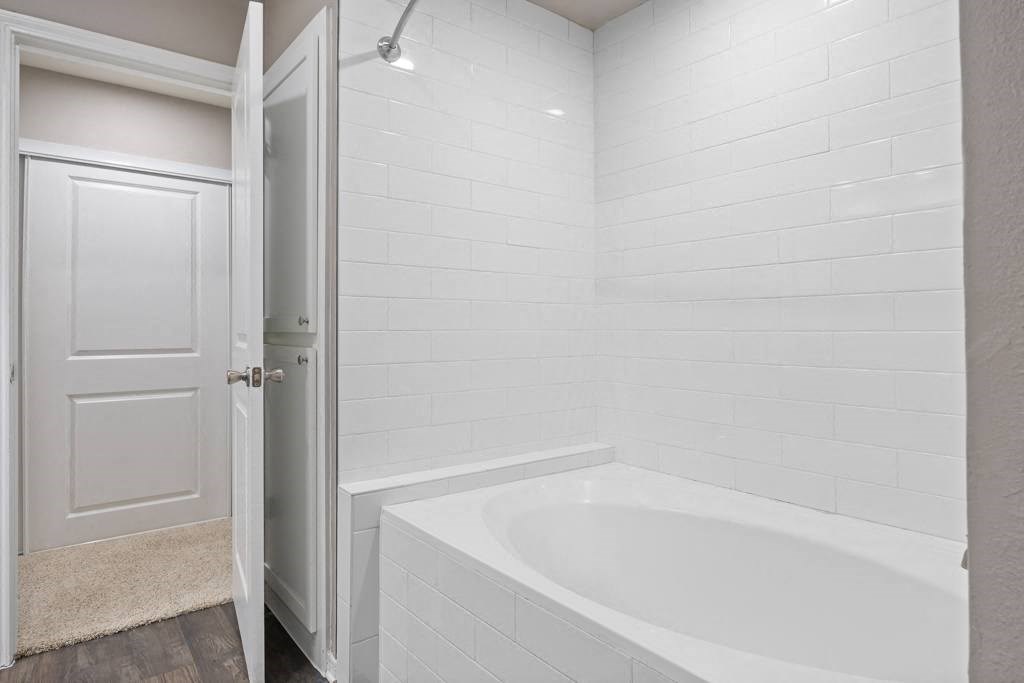 a bathroom with a bathtub and a door at Waters Edge Apartment Homes, Georgetown, TX, 78626