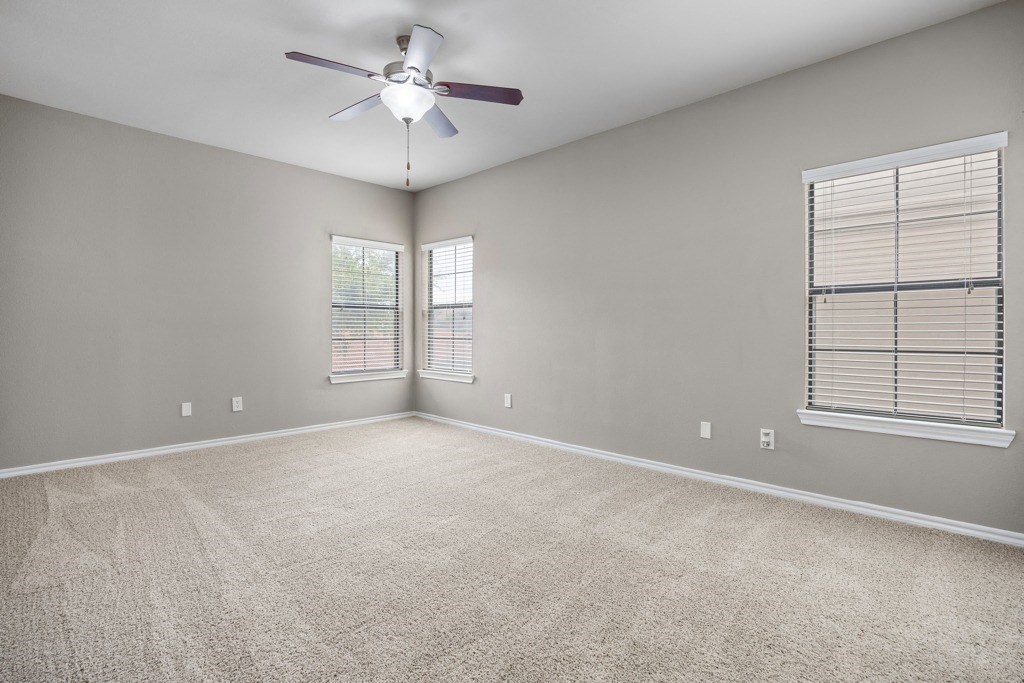 an empty room with a ceiling fan and two windows at Waters Edge Apartment Homes, Georgetown, 78626