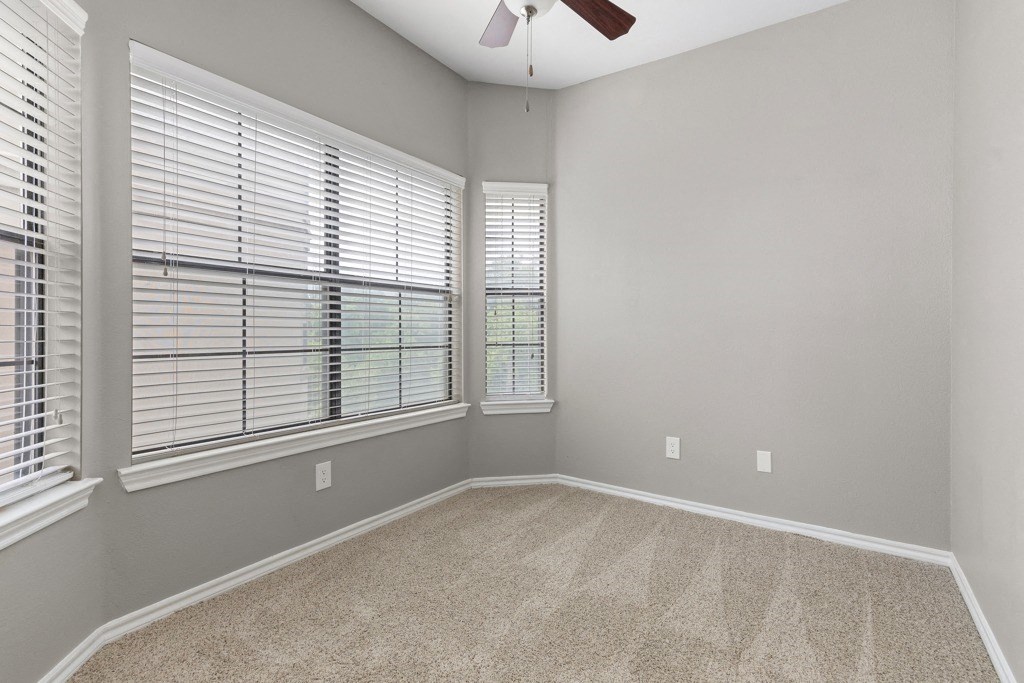 a bedroom with two large windows and a ceiling fan at Waters Edge Apartment Homes, Georgetown, TX