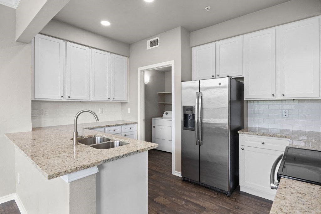 a kitchen with white cabinets and a stainless steel refrigerator at Waters Edge Apartment Homes, Georgetown, TX, 78626