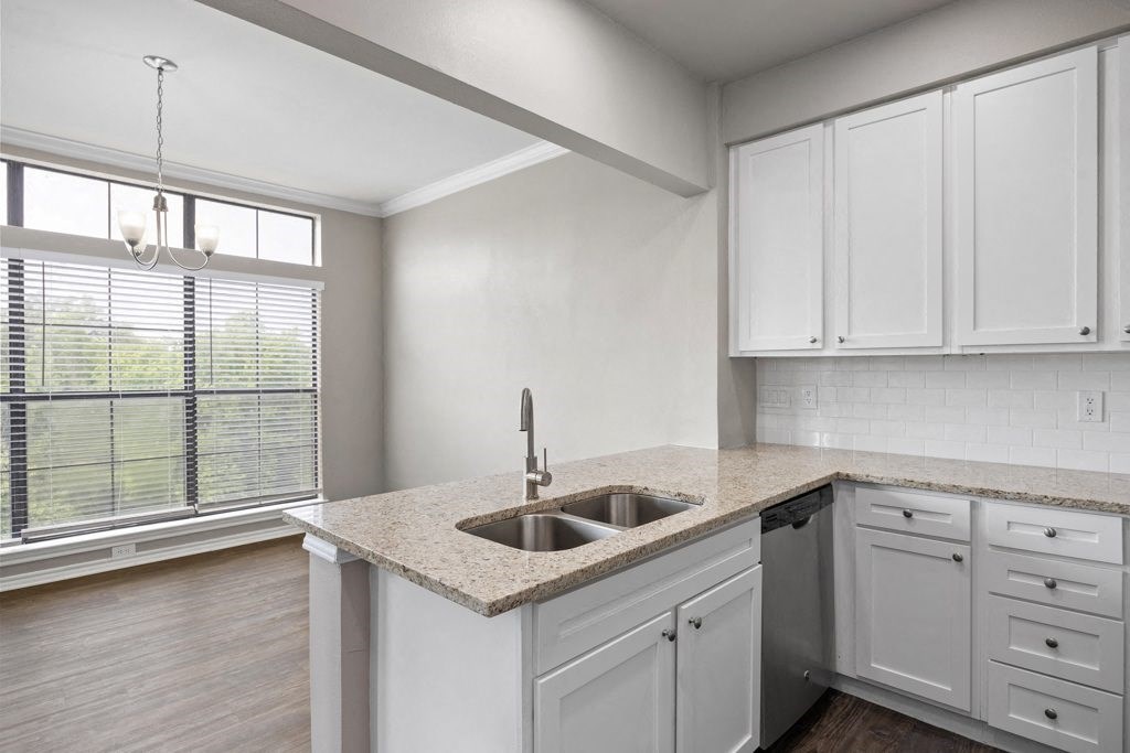 a kitchen with white cabinets and a large window at Waters Edge Apartment Homes, Texas