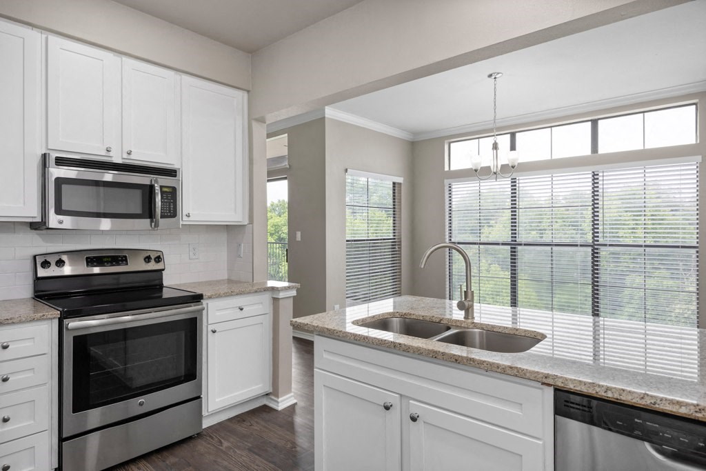 a kitchen with white cabinets and a large window at Waters Edge Apartment Homes, Texas, 78626
