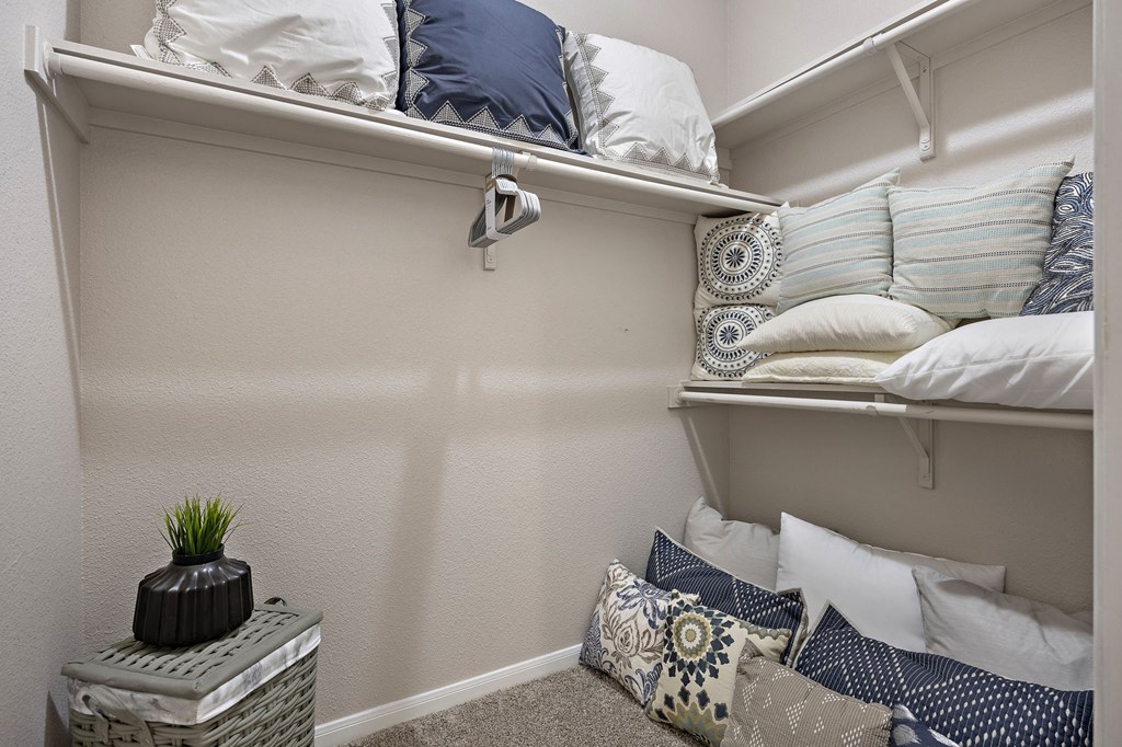 a walk in closet in a bedroom with pillows on the floor and a shelf with pill at Artisan Apartments & Shops, Austin, Texas