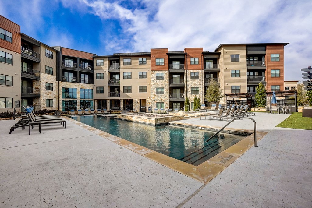 a swimming pool with an apartment building in the background a swimming pool with an apartment building in the background at Aurora Watson Branch, Mansfield, TX, 76063