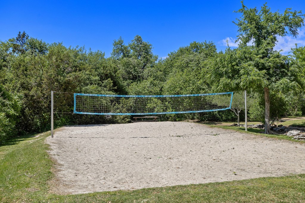 the volleyball court is located in front of the trees at Lakeline East Apartments, Cedar Park