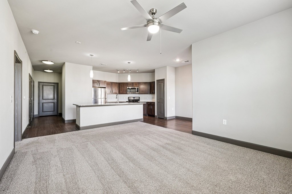 A spacious living room with a carpeted floor and a ceiling fan.