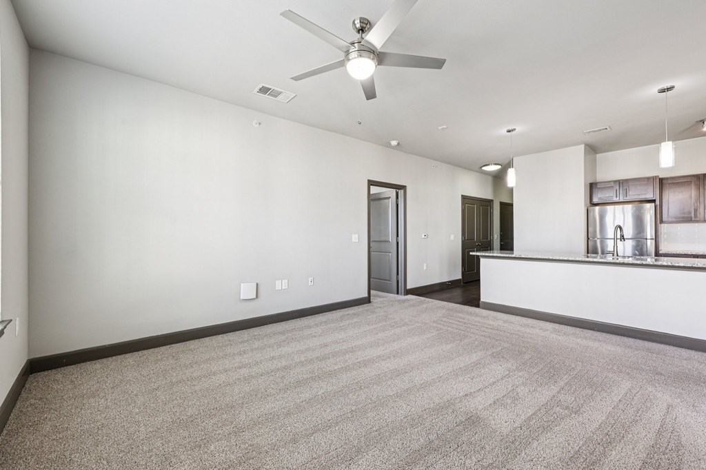 A room with a ceiling fan and carpeted floor.