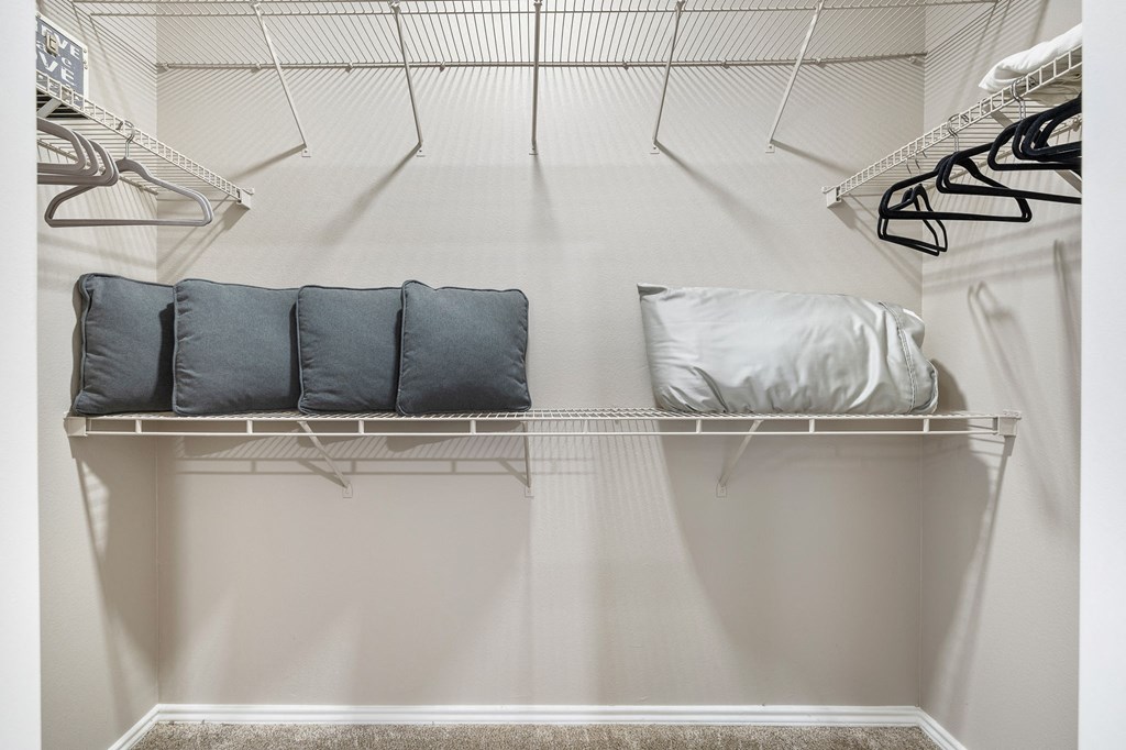 a walk in closet with white walls and shelves and a closet organizer with pillows at Sonterra Apartment Homes, Texas, 78726