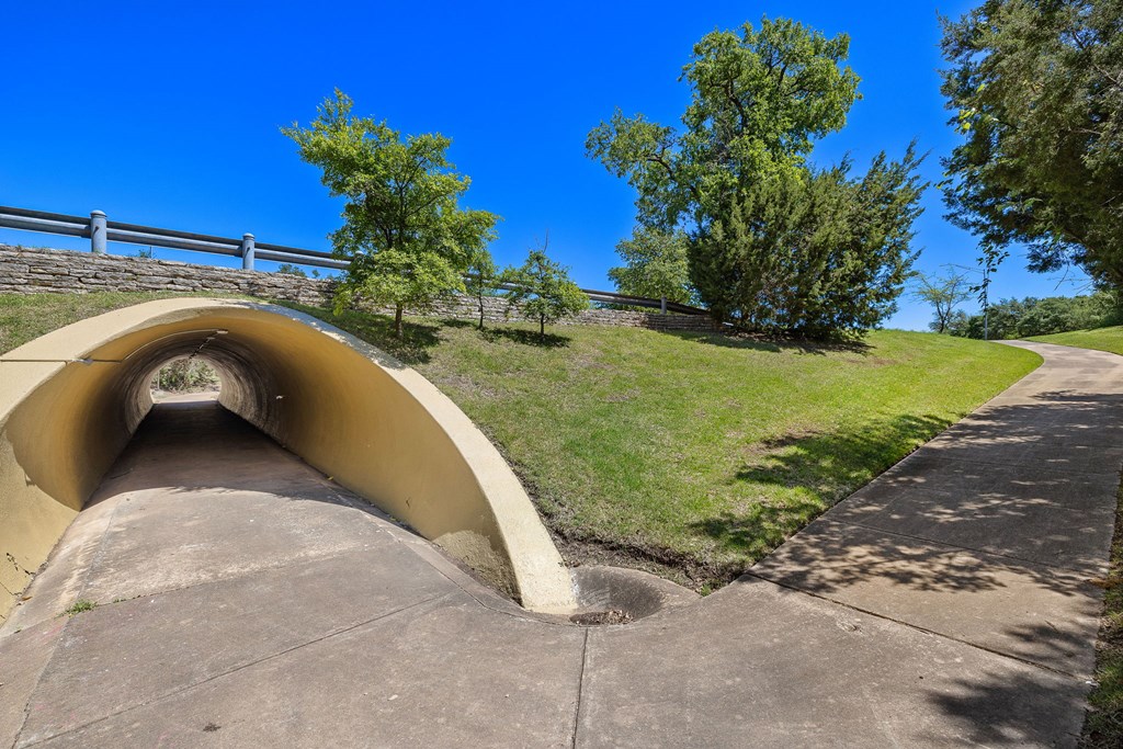 a tunnel on the side of a hill with grass and trees at Lakeline East Apartments, Cedar Park, TX