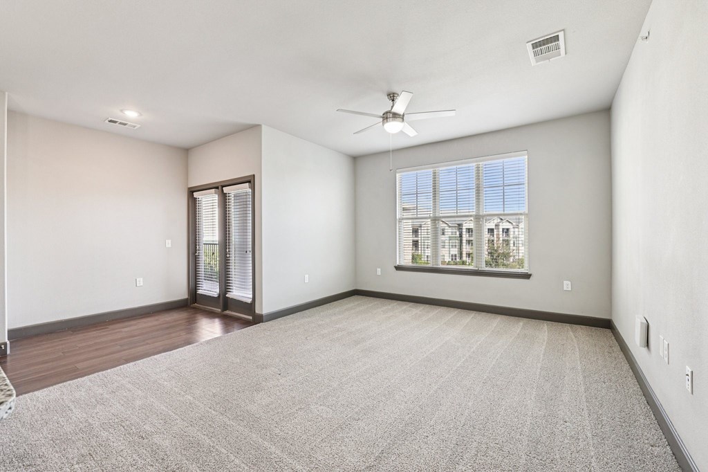 A room with a carpeted floor and a ceiling fan.