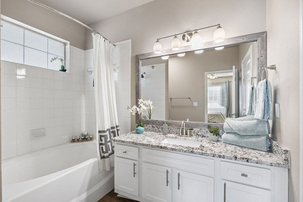 a bathroom with a sink and a mirror and a tub at Sonterra Apartment Homes, Austin, TX