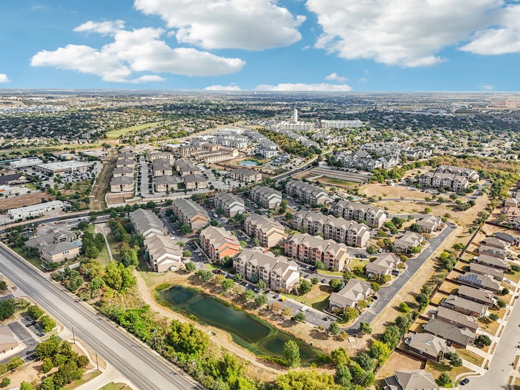 A bird's eye view of a residential area with apartment buildings, roads, and a body of water.