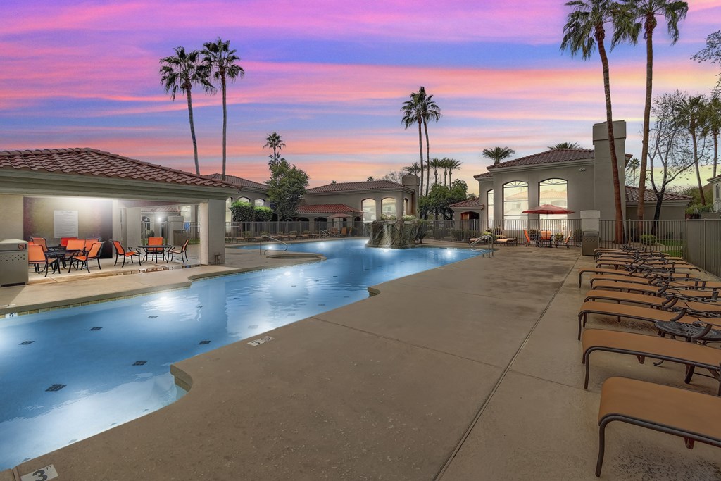 A swimming pool with lounge chairs and palm trees at San Montego Apartments, Arizona
