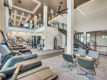 a gym with cardio machines and chairs and a spiral staircase at Aurora Watson Branch, Mansfield, TX