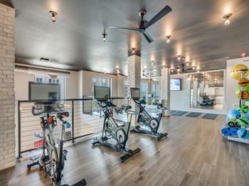 a gym with treadmills and other exercise bikes and a tv at Aurora Watson Branch, Mansfield, Texas