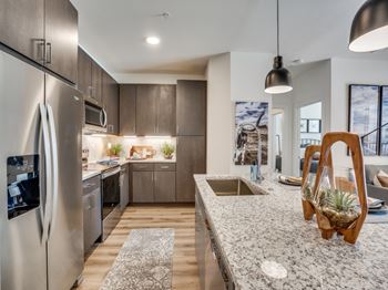 A modern kitchen with a stainless steel refrigerator and wooden cabinets. at Aurora Watson Branch, Mansfield