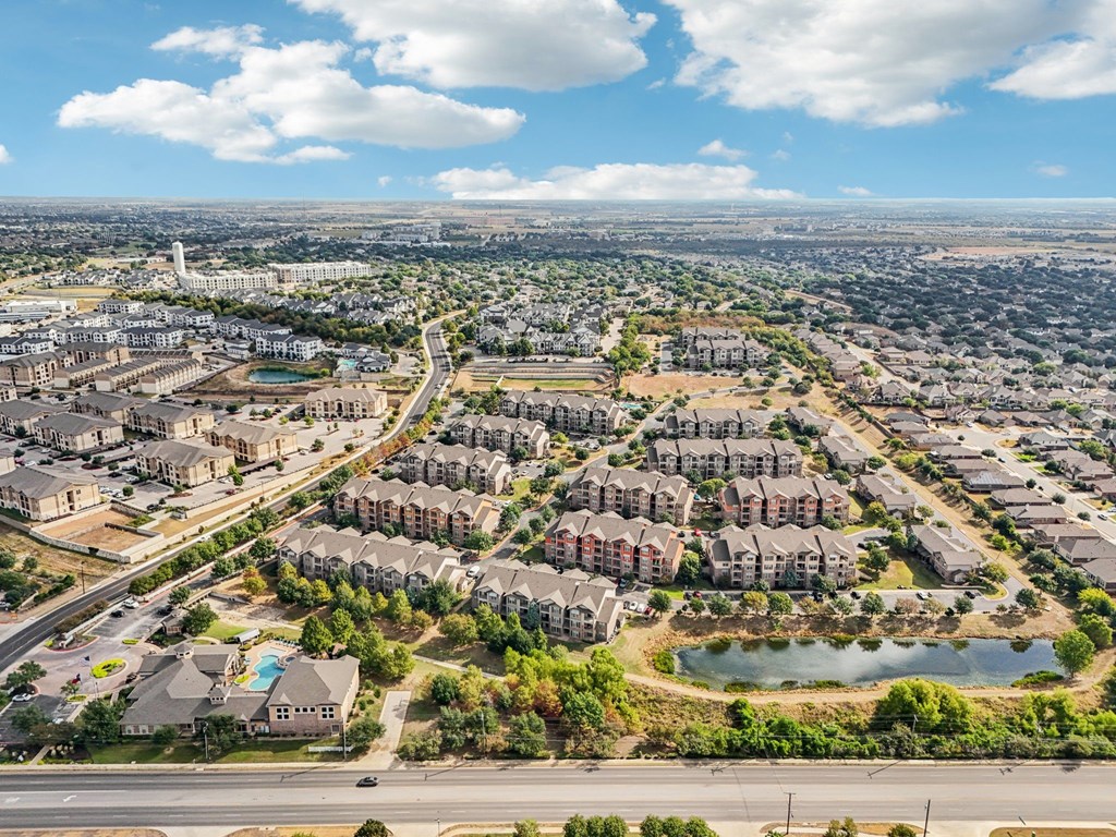 A bird's eye view of a residential area with multiple apartment buildings and a lake.