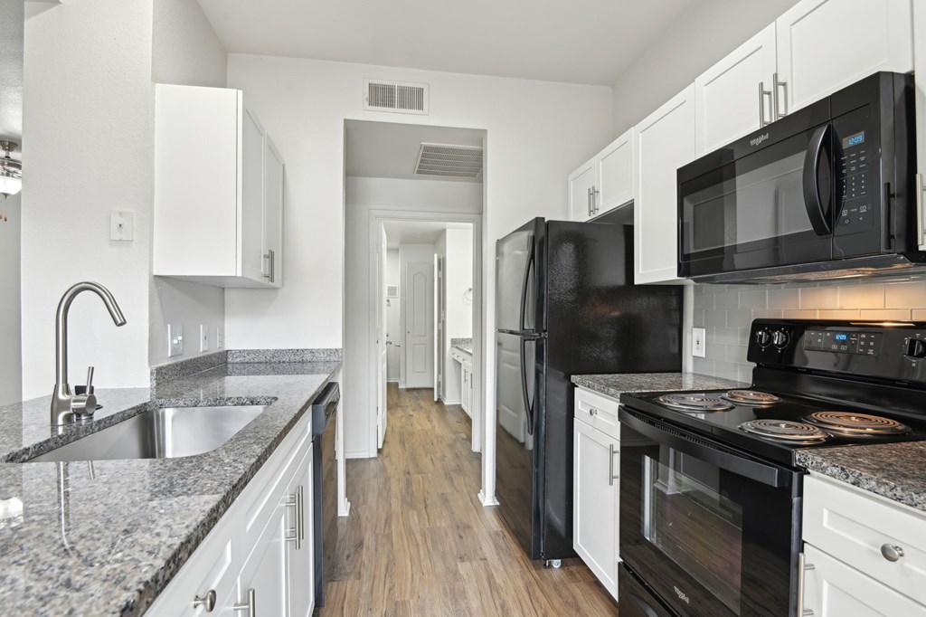 A kitchen with black appliances and white cabinets.