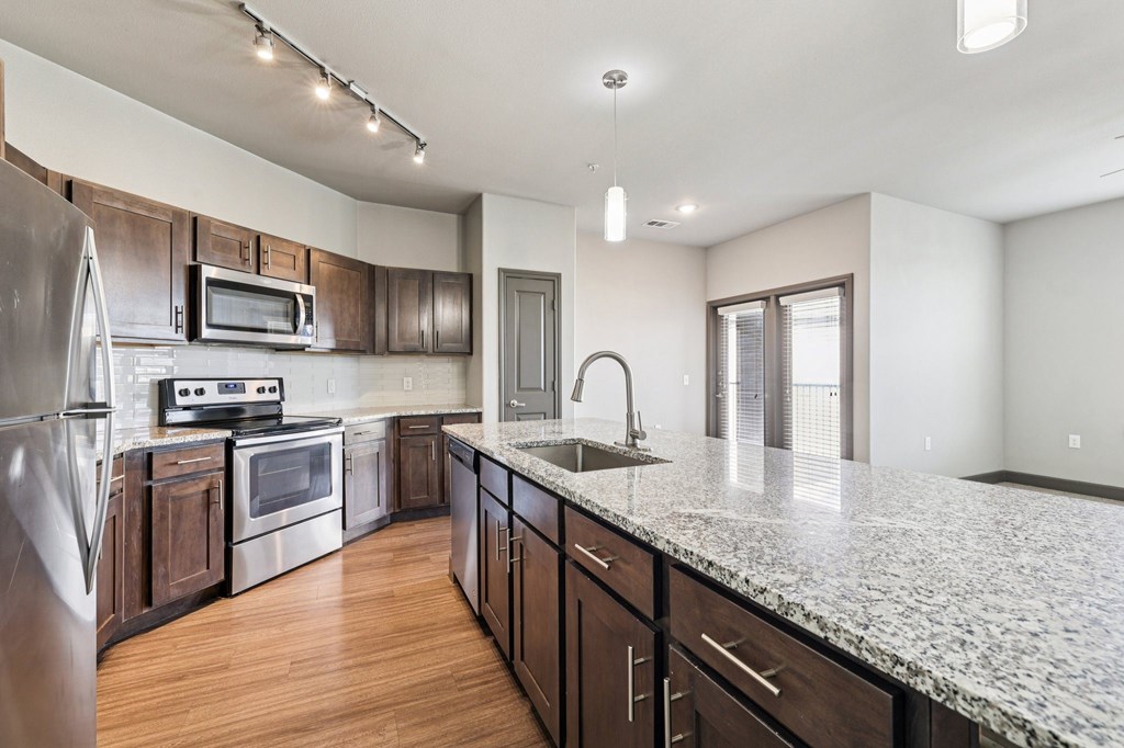 A kitchen with a granite countertop and stainless steel appliances.