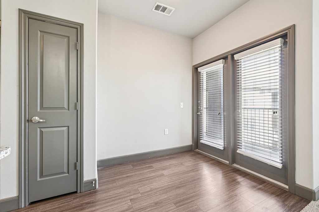 A room with a grey door and a window with blinds.