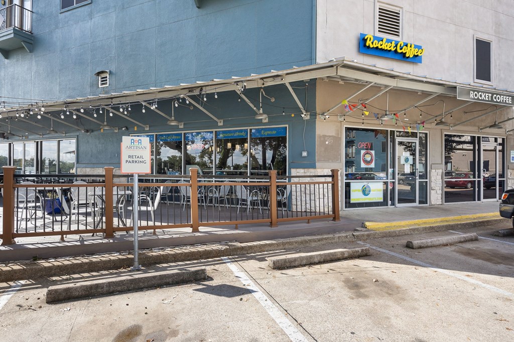a city street with a brown fence and a blue building in the background at Artisan Apartments & Shops, Austin, TX
