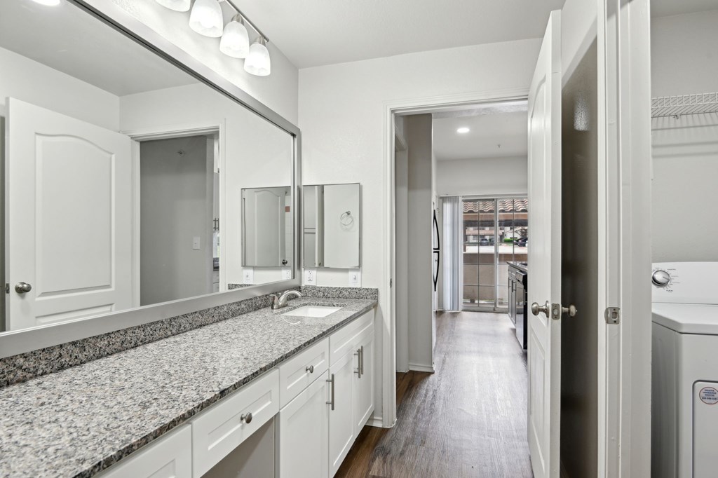 A bathroom with a granite countertop and white cabinets.