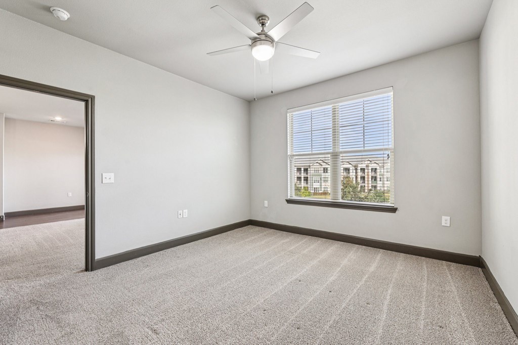 A room with a ceiling fan and a window with blinds.