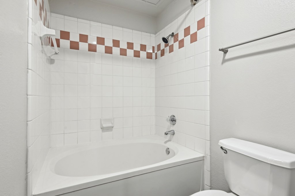 A white bathroom with a tub and toilet.