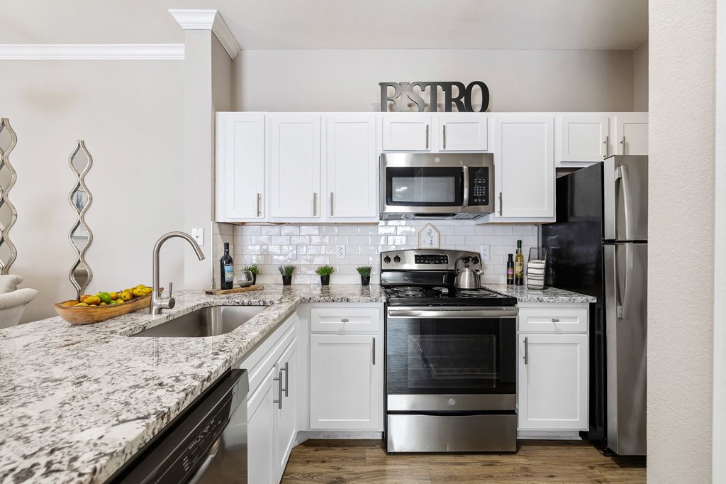 a white kitchen with stainless steel appliances and granite counter tops at Sonterra Apartment Homes, Austin, Texas