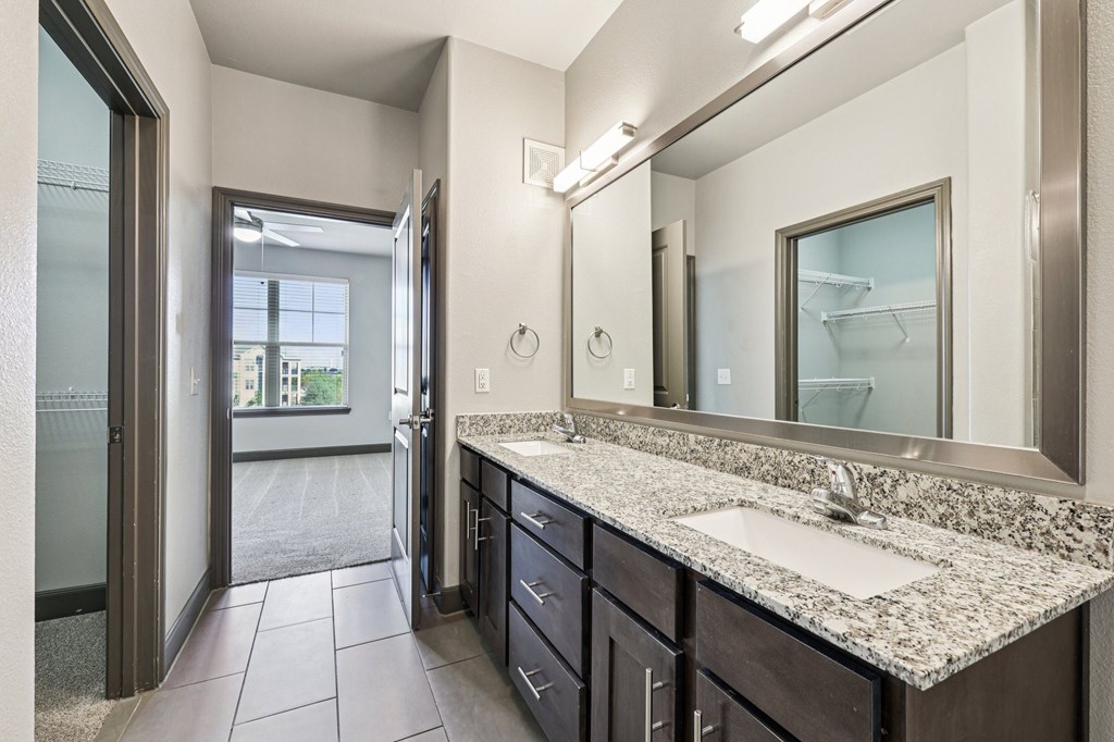A bathroom with a sink, mirror, and a large window.