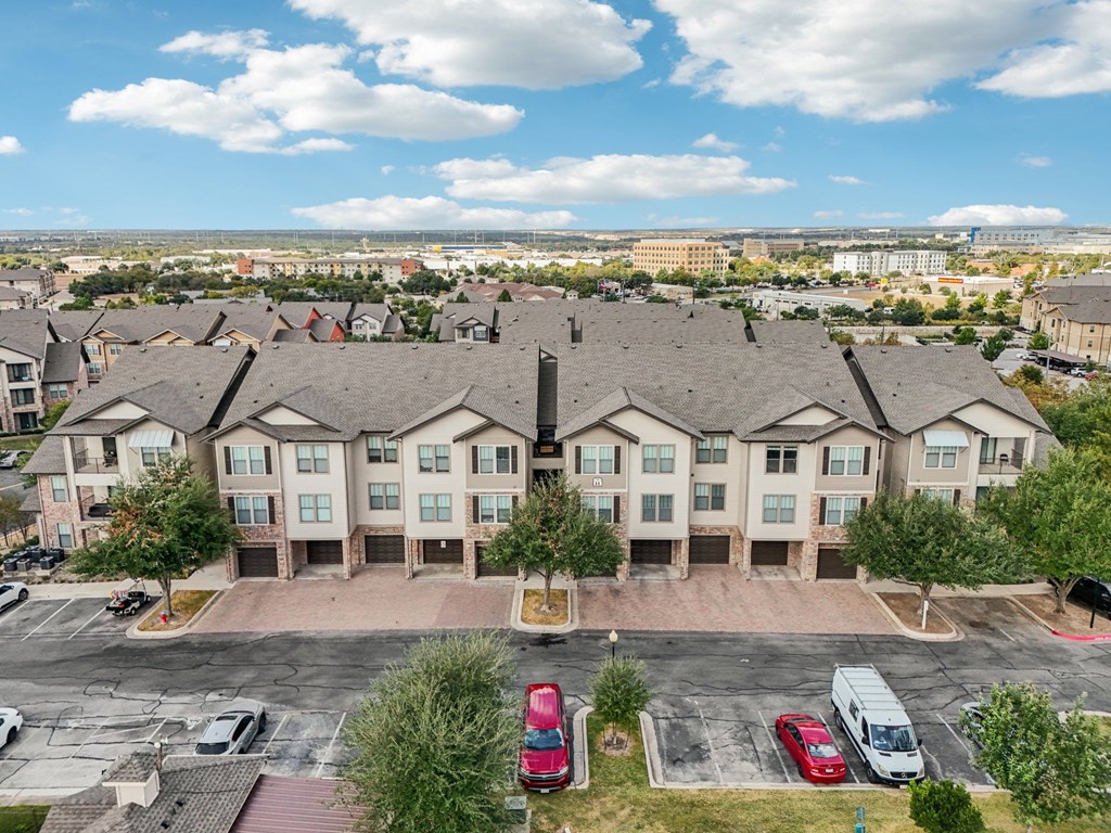 A large apartment complex with a parking lot in front.