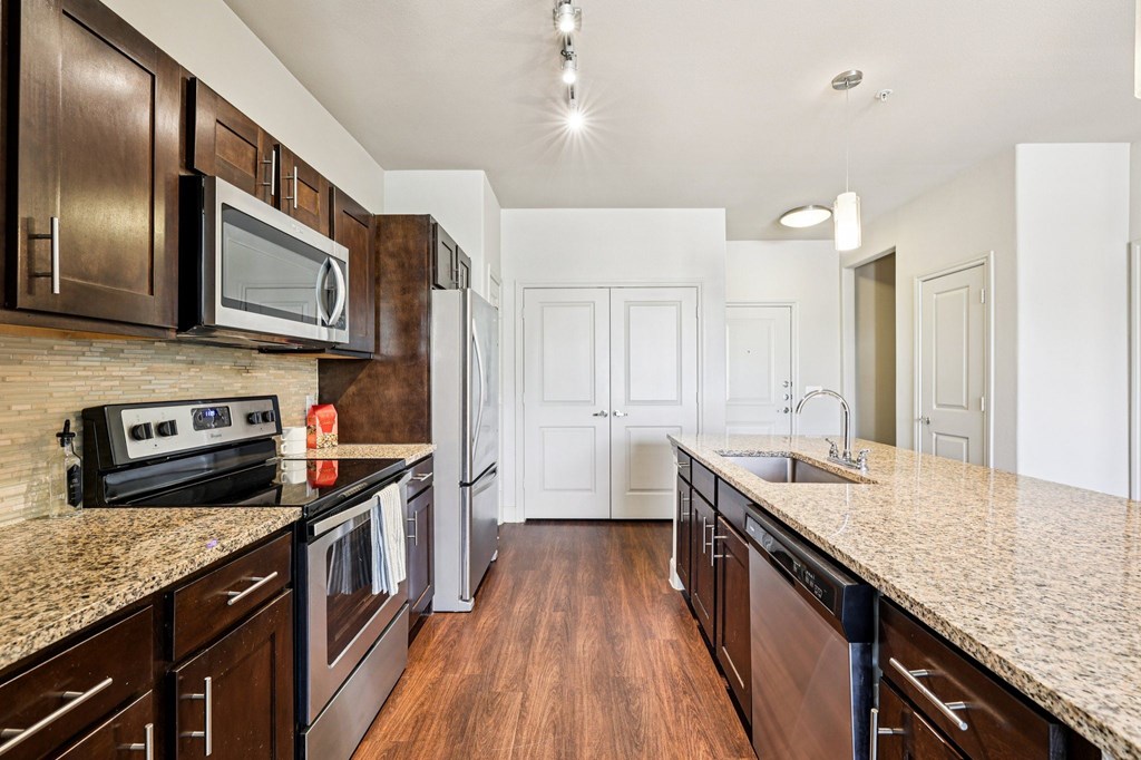 A kitchen with dark brown cabinets and granite countertops.