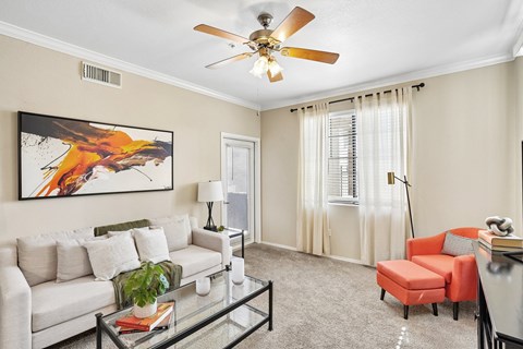 A living room with a white couch, a red chair, and a painting on the wall.