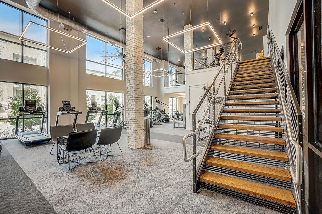 the landing of the staircase in the lobby of a building with a gym and chairs at Aurora Watson Branch, Texas