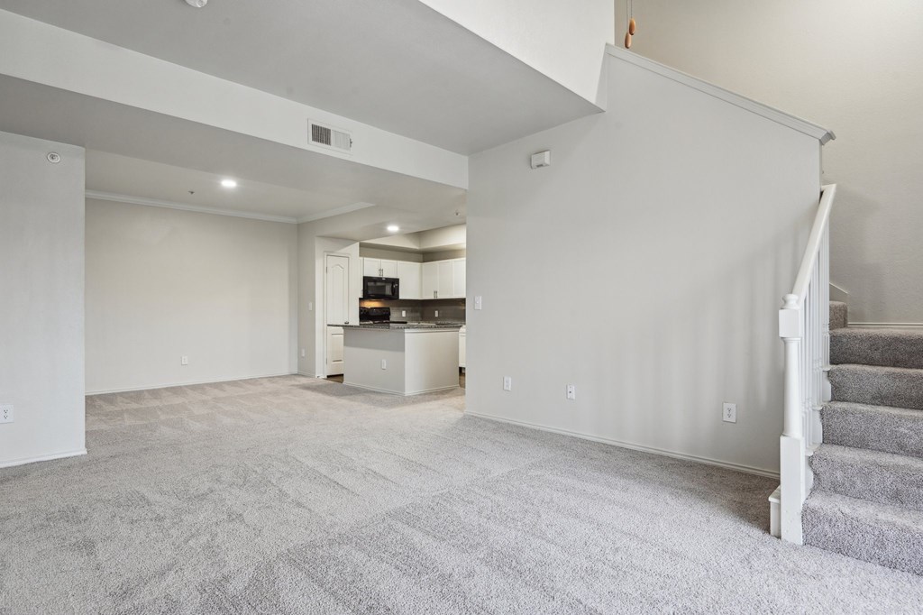A spacious living room with a staircase on the right side.