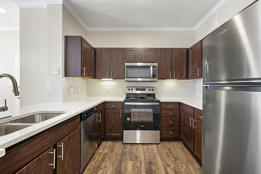 a kitchen with stainless steel appliances and wooden cabinets at The Verandah, Austin, TX, 78726