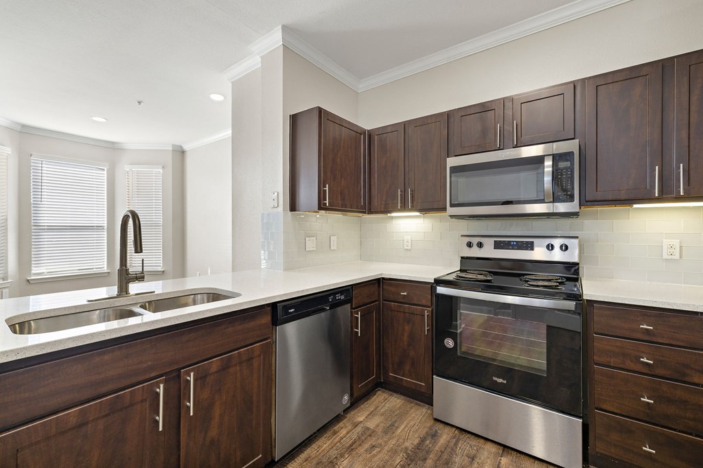 a kitchen with wooden cabinets and stainless steel appliances at The Verandah, Austin, TX