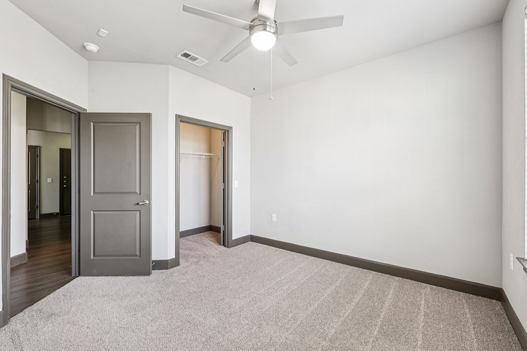 A room with a ceiling fan and a rug on the floor.